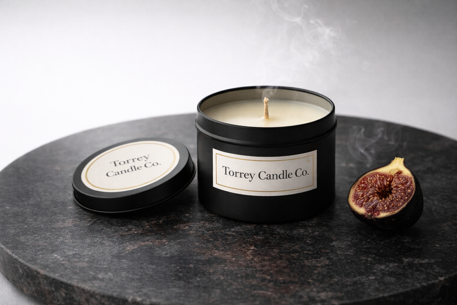 Torrey Candle Co. candle with lid on a dark surface, accompanied by a fig.