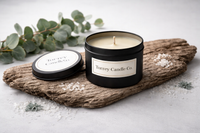 Torrey Candle Co. candle on a wooden log with eucalyptus leaves and small flowers.